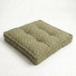 Green cushion with a subtle pattern on a white background