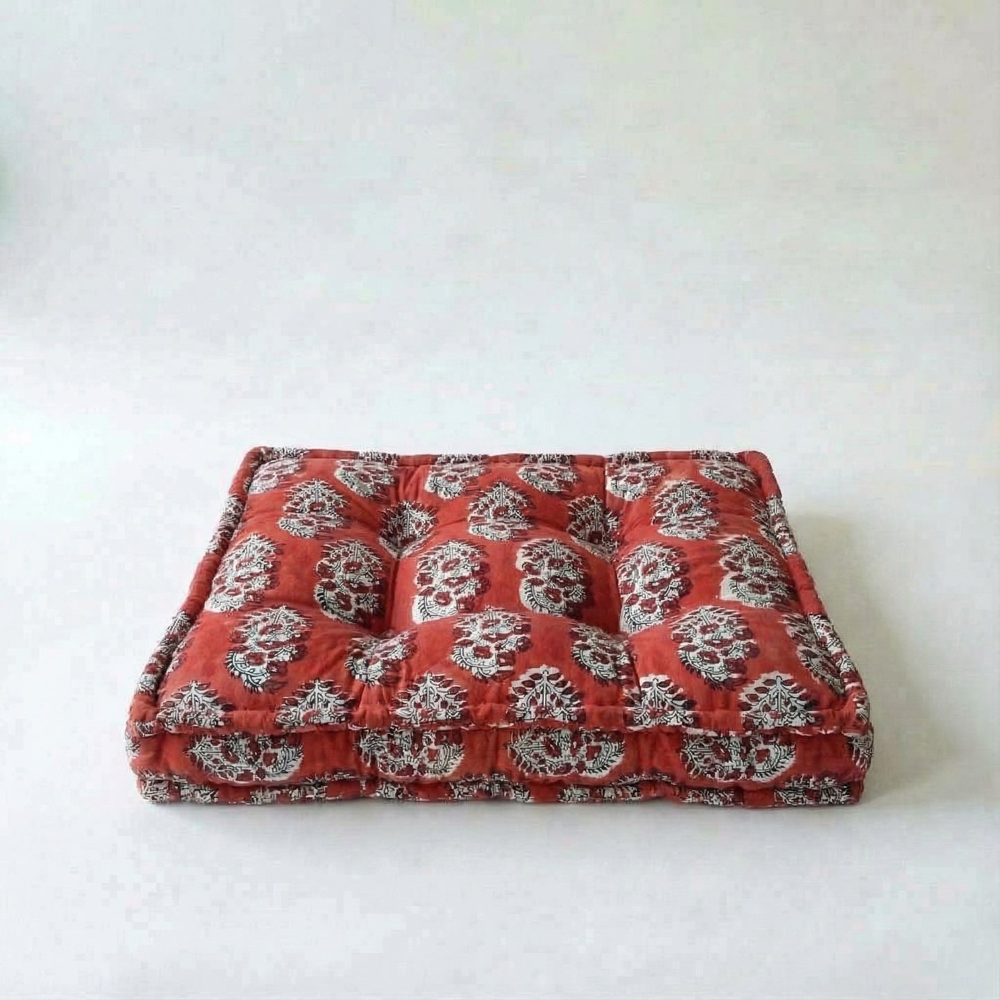 Red dog bed with white floral pattern on a white background