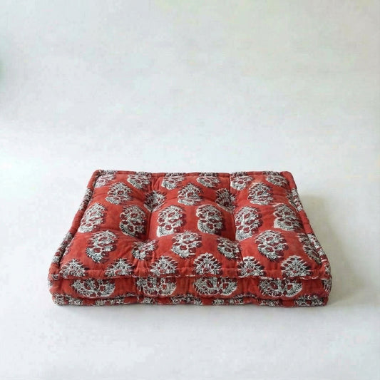 Red dog bed with white floral pattern on a white background