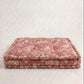 A pet bed with a dusty rose and beige floral toile pattern, set against a neutral textured light gray background.