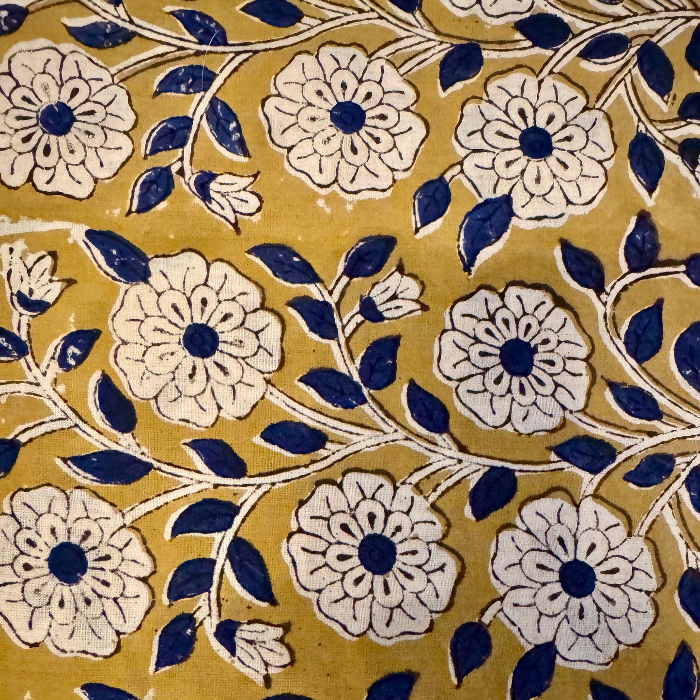 Pattern of white flowers with blue centers on a yellow background