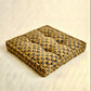Yellow blue and green print pet bed on a beige background